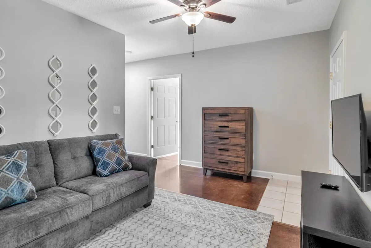 A cozy interior space with a stylish sofa, decorative wall art, a dresser, and a television, arranged for group entertainment and relaxation. The setting suggests opportunities for movie nights, games, and shared experiences between adventures.