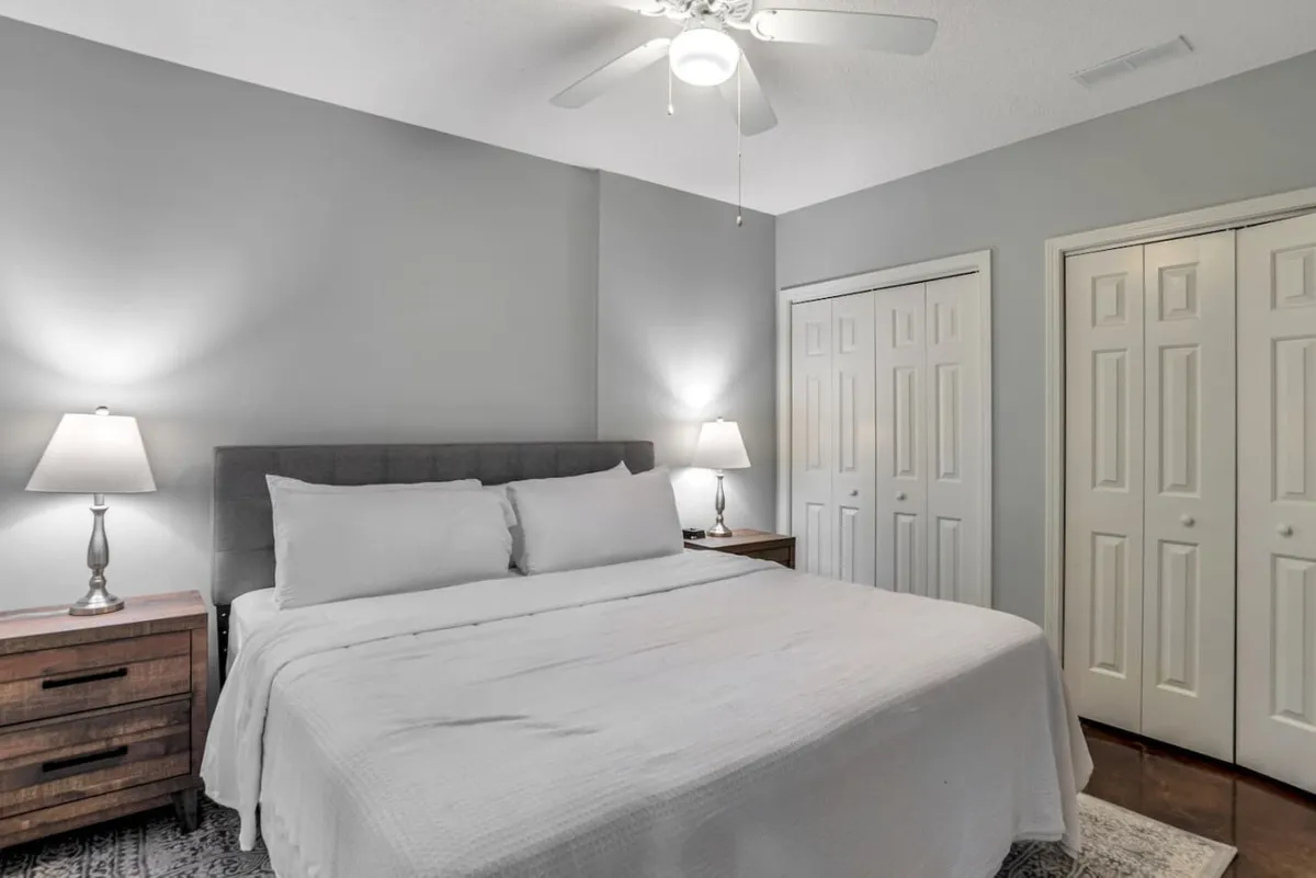 A tranquil bedroom featuring a cozy bed, matching nightstands and lamps, and ample closet space. The room is softly lit, suggesting a peaceful space for reading or unwinding, with subtle contemporary touches in the decor and furnishings.