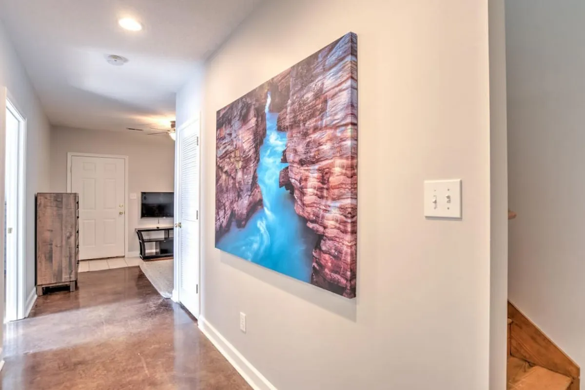 A calm and inviting hallway featuring a large artwork depicting a canyon with water. The space is bright and subtly hints at the outdoors through the artwork, which offers a sense of exploration and connection to nature.